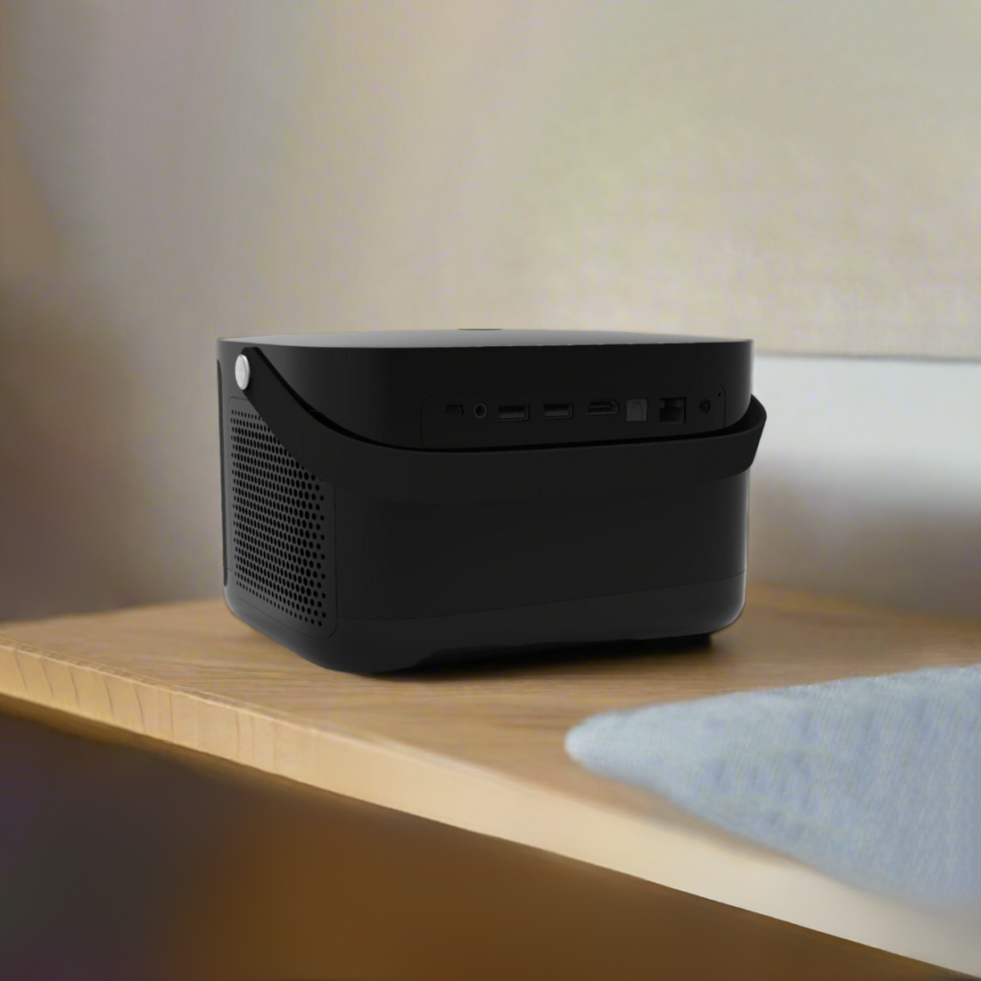 Black projector on a wooden table with a blurred indoor background